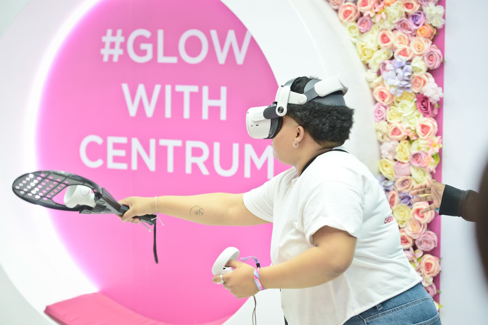 A visitor playing VR padel in front of the #GlowWithCentrum ring